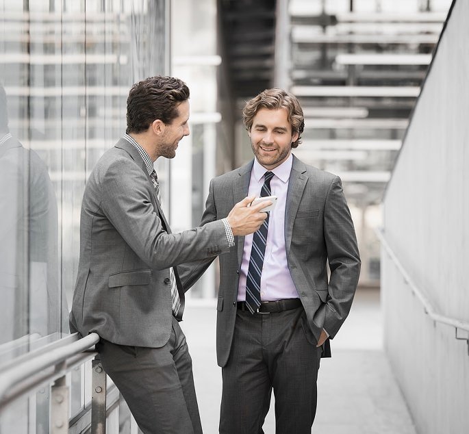 Dos ejecutivos con traje conversando en un entorno empresarial moderno, representando la búsqueda y selección de talento C-Level con confidencialidad y experiencia.